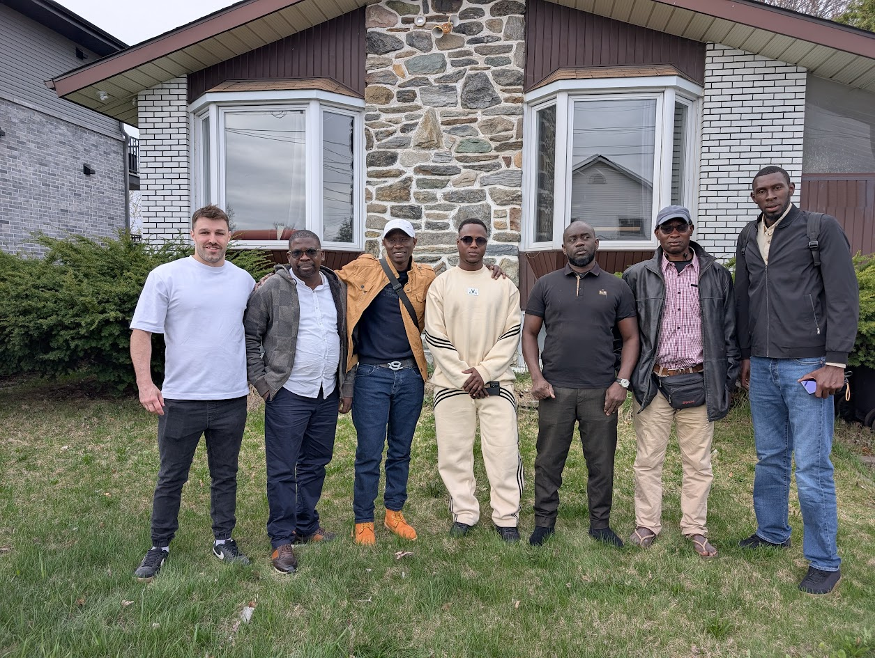 Un groupe de travailleurs nouvellement arrivés, réunis devant la maison où ils s’installent.