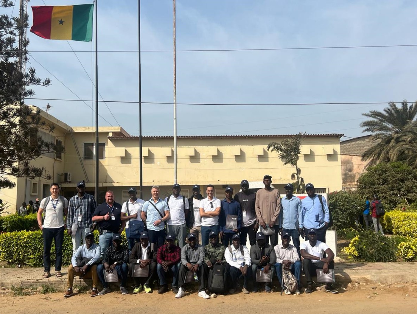 Cohorte de travailleurs sélectionnés lors d’une mission de recrutement international, devant le lieu de formation, drapeau du Sénégal visible
