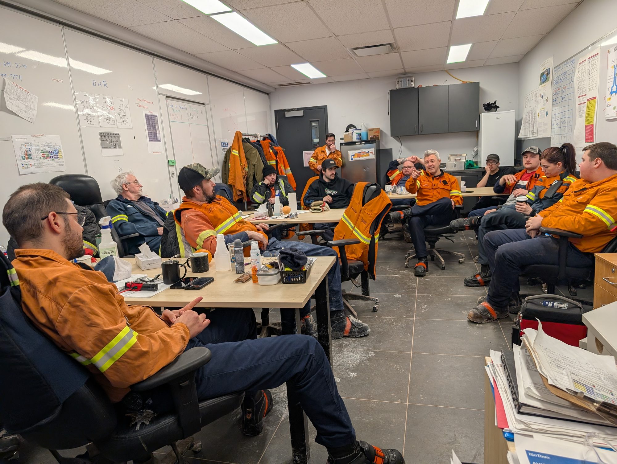 Rencontre d’équipe en salle de pause d’une usine, gestionnaire et opérateurs en vêtements de travail assis en cercle