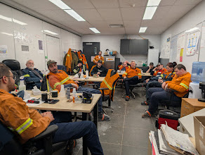 Une rencontre d’équipe tenue dans une salle de chantier, avec des travailleurs en vêtements haute visibilité.