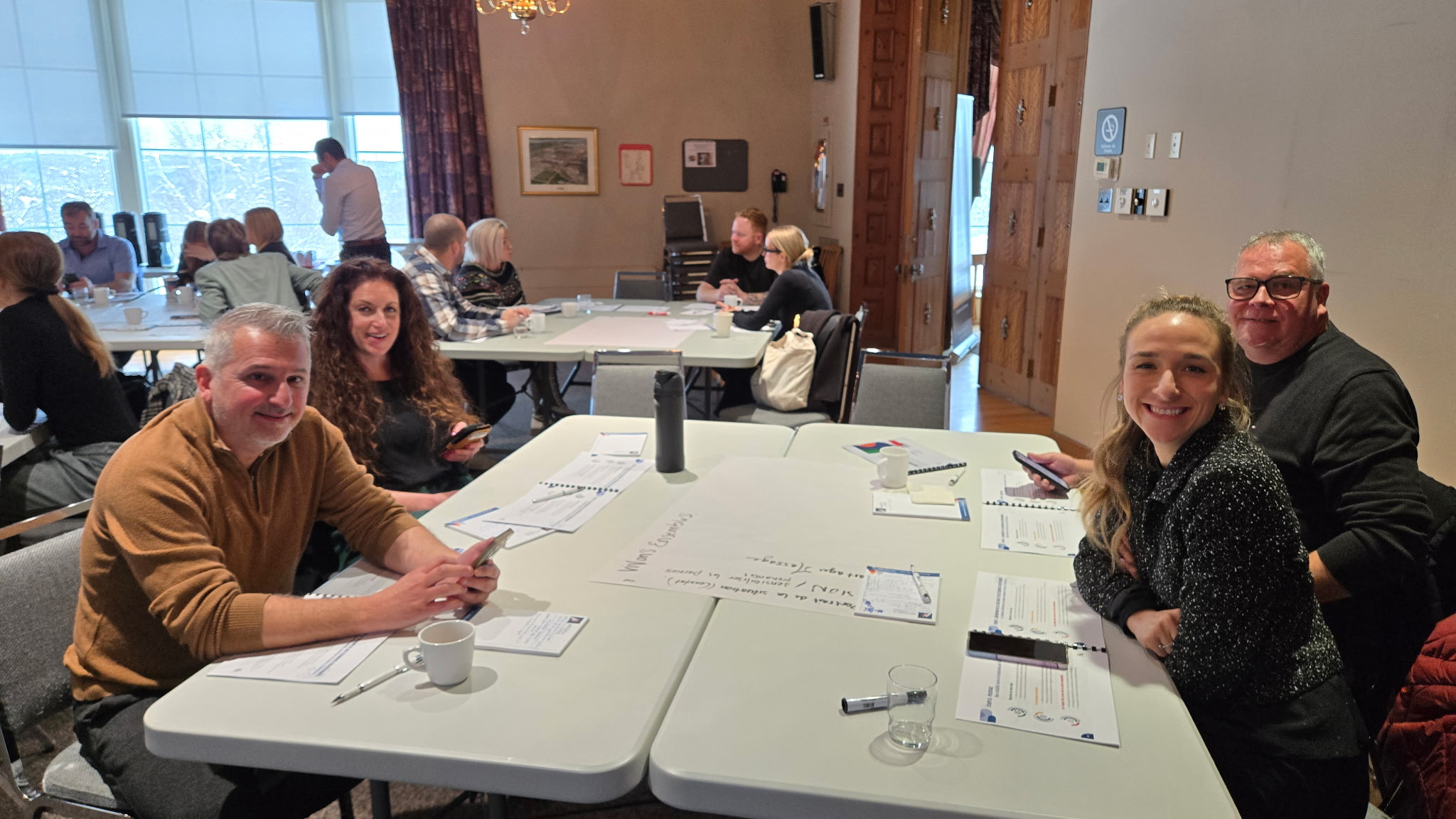 Groupe de participants réunis autour d'une table, salle de rencontre du Manoir du Saguenay